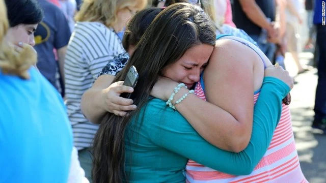 Một nữ sinh may mắn sống sót sau vụ xả súng ôm chầm lấy người thân bên ngoài khuôn viên trường. Ảnh: AP