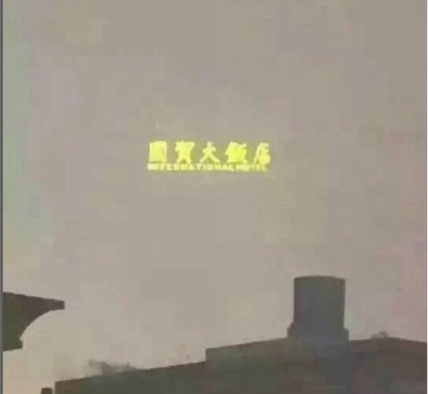 
Nhiều tòa nhà bị khói bụi che mờ, chỉ còn bảng hiệu chiếu đèn hiện lên - Ảnh: Weibo

 
