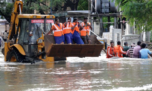 Công nhân cứu hộ di chuyển trên đường phố ngập lụt bằng xe ủi ở Chennai.