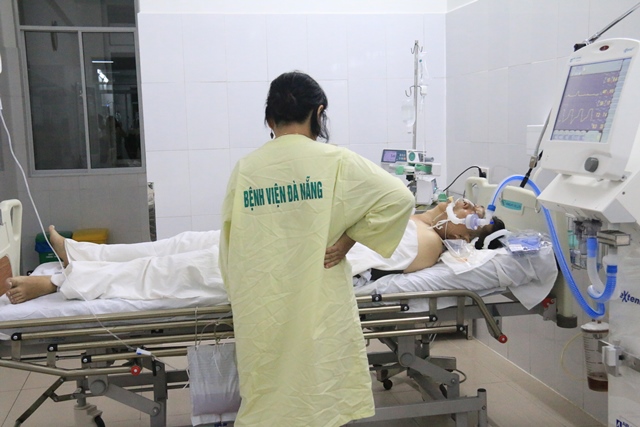 Chị Thu đang chăm sóc chồng bị thương do lật thuyền ở bệnh viện
