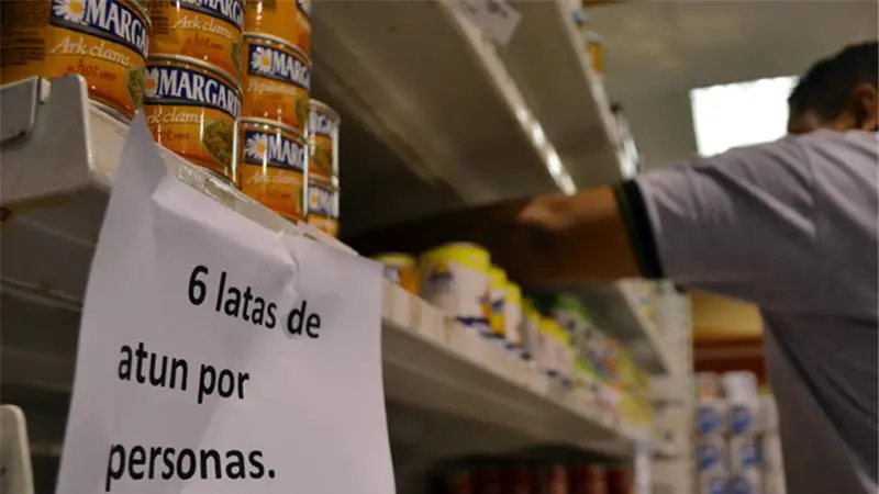 
Tấm biển Mỗi người chỉ mua 6 can. Xin cảm ơn được dán tại một siêu thị Caracas. Ảnh: EPA
