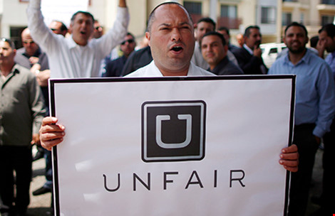 Một người biểu tình phản đối ứng dụng Uber là “Không công bằng” với các hãng taxi. Ảnh: Reuters