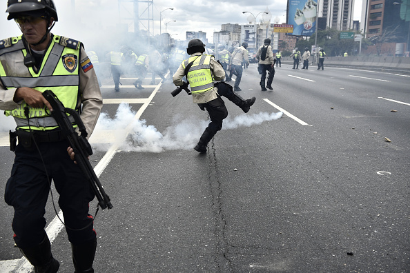 
Cảnh sát đá quả lựu đạn hơi cay ra xa trong cuộc đụng độ với người biểu tình. Nhằm tiết kiện điện, chính phủ Venezuela chỉ mở cửa một số cơ quan nhà nước 2 buổi mỗi tuần. Ảnh: Getty
