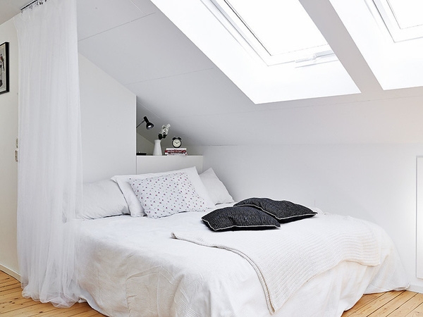 Một phòng ngủ khiêm tốn được bố trí tại một góc phòng và được ngăn cách với các không gian khác bởi tấm rèm trắng.