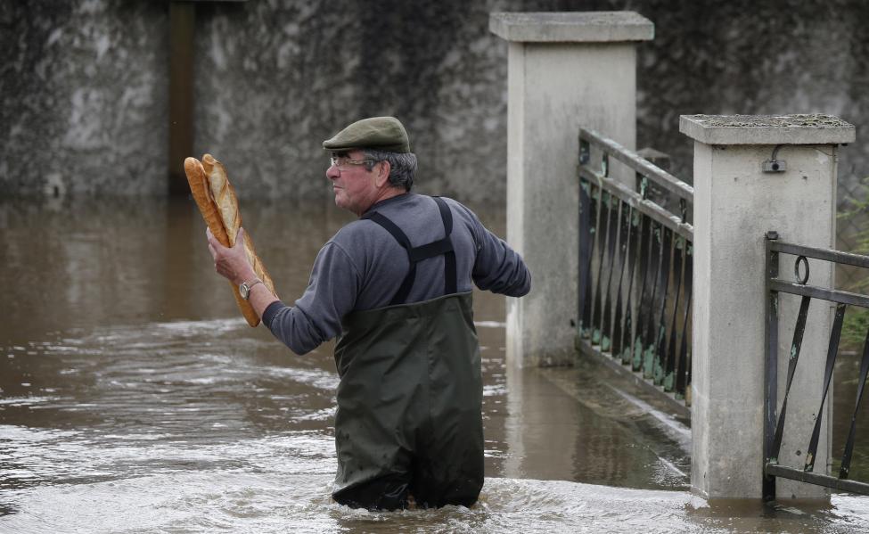 
Một người đàn ông đang mang hai chiếc bánh mì baguettes truyền thống của Pháp về nhà. Ảnh: Christian Hartmann / Reuters

