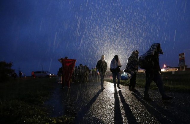 Những bóng người di cư đi lại dưới cơn mưa nặng hạt ở biên giới Áo - Hungary - Ảnh: AP