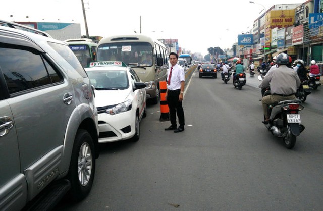Một tài xế taxi bước ra ngoài quan sát tình hình kẹt xe trên đường Nguyễn Oanh - Ảnh: Q.Khải