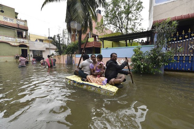 Người dân phải dùng nệm để làm bè tạm di chuyển trên đường ngập lụt.
