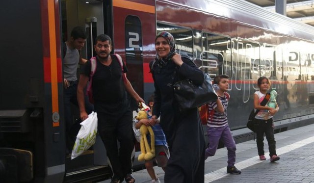 Người tị nạn tươi cười bước ra khỏi chuyến tàu hoả tại Áo - Ảnh: Reuters
