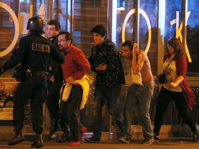 Lực lượng đặc nhiệm của Pháp đang sơ tán người dân khỏi nhà hát. Một người đàn ông bị thương đang ôm đầu.