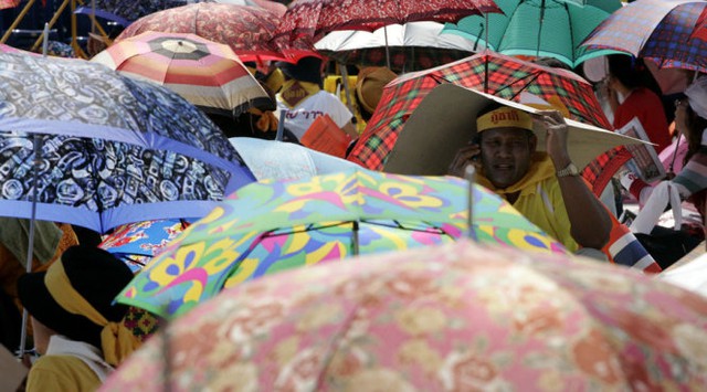 Người dân che nắng đi trên đường ở Thái - Ảnh: Reuters