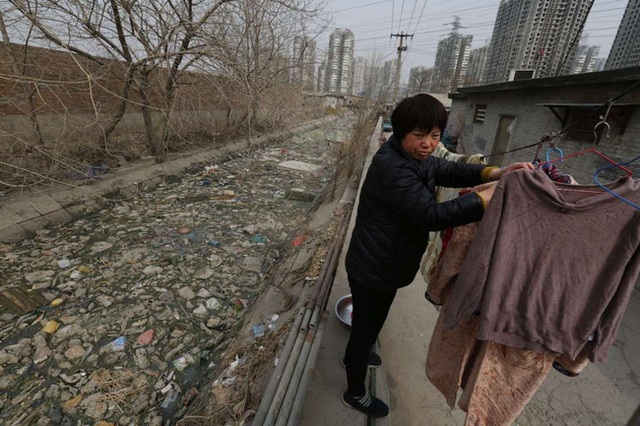 Người dân đang phơi quần áo bên cạnh dòng sông ngập rác ở Bắc Kinh, Trung Quốc.