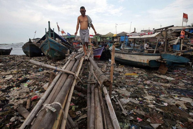 Một người dân Indonesia đi bộ trên bãi biển ô nhiễm ở Jakarta.