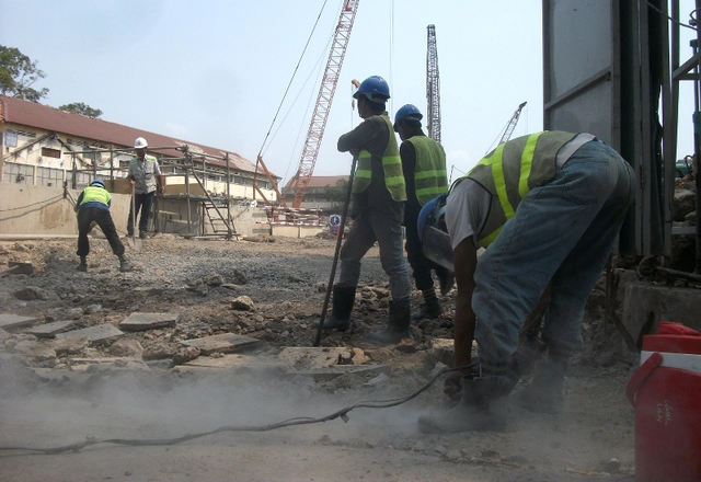 
Công nhân dùng máy khoan thay nhau đẩy đất còn dính lại từ các trụ sắt tạm dùng để đỡ sàn.
