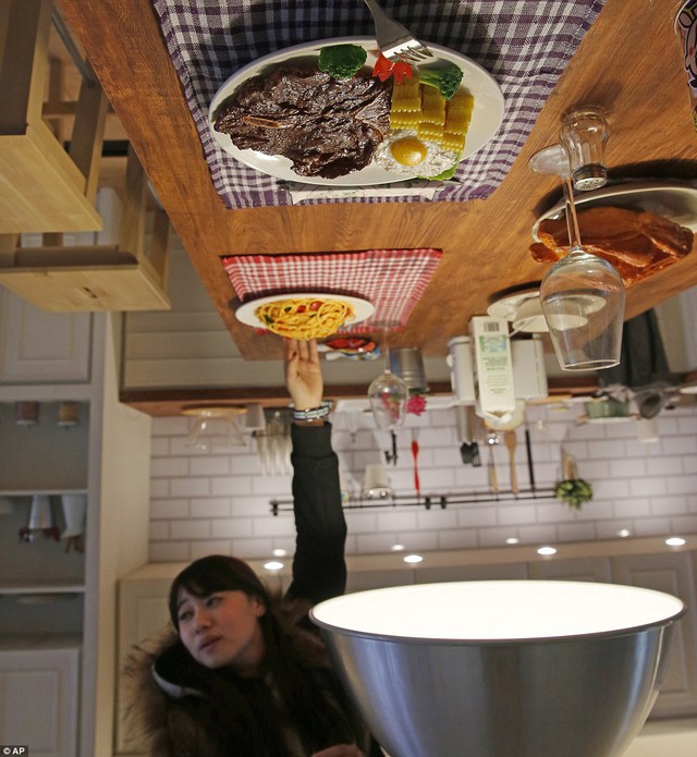 Một khách du lịch thích thú với một đĩa mì spaghetti nhựa đã được gắn chặt vào một bảng trên trần phòng bếp.