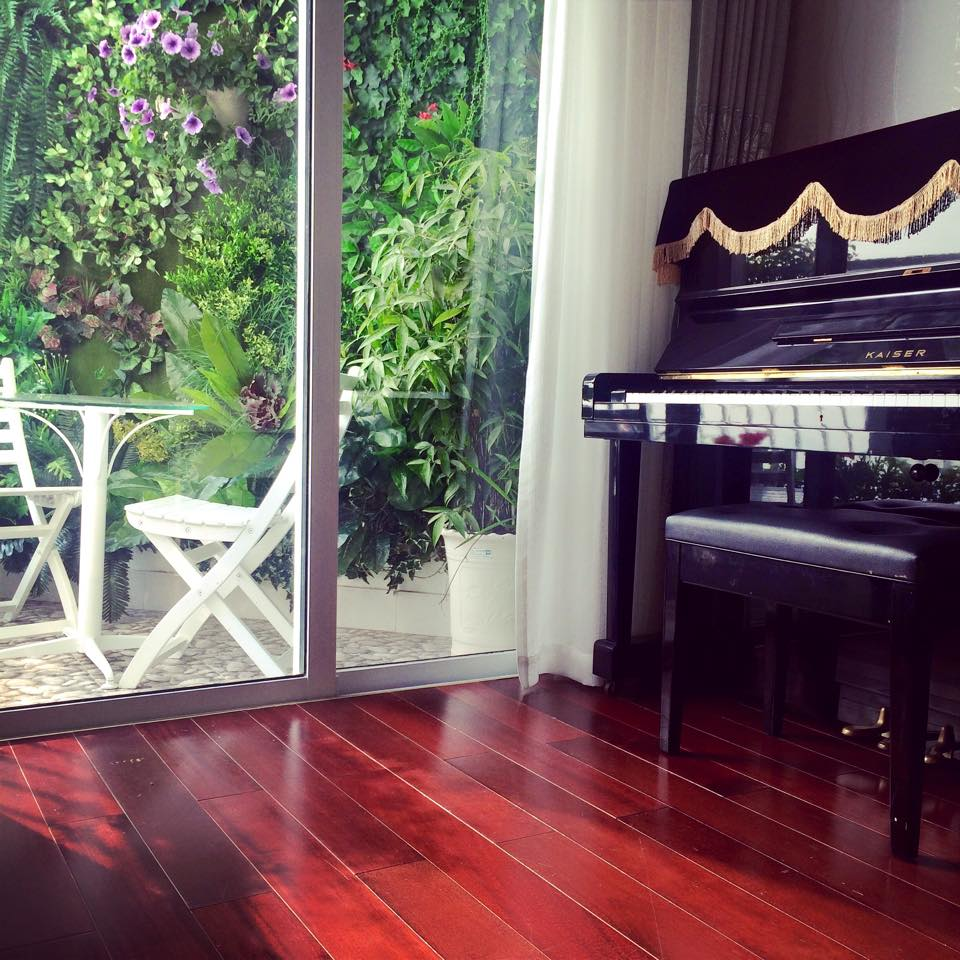 Góc đặt piano cạnh ban công đầy nắng, gió và hoa cỏ trong căn hộ.