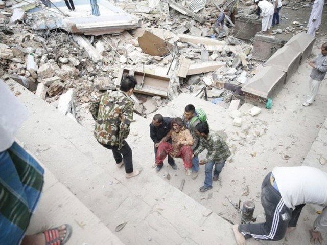 Một nhóm người “khiêng” phụ nữ ra khỏi tòa nhà bị sụp đổ ở thủ đô Kathmandu, Nepal - Ảnh: EPA