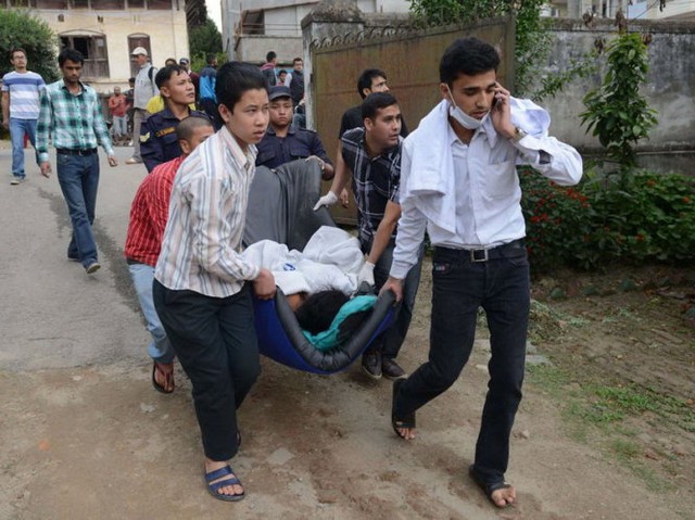Một nhóm người khiêng người bị thương đến lên xe đưa đến cấp cứu tại bệnh viện thủ đô Kathmandu - Ảnh: Getty Images