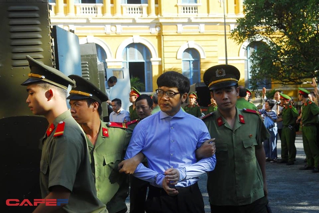 
Trước giờ xét xử, Phan Thành Mai, nguyên Tổng giám đốc Ngân hàng Xây dựng xuất hiện trong chiếc áo dài tay màu xanh với cổ được cài kín và đôi tay bị còng.
