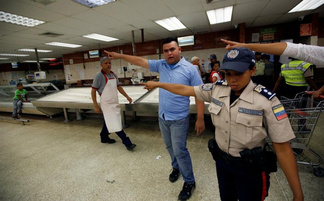 Nhân viên siêu thị và cảnh sát hướng dẫn người dân xếp hàng mua thực phẩm và hàng hóa thiết yếu tại một siêu thị ở Venezuela hôm 30/6 - Ảnh: Reuters.
