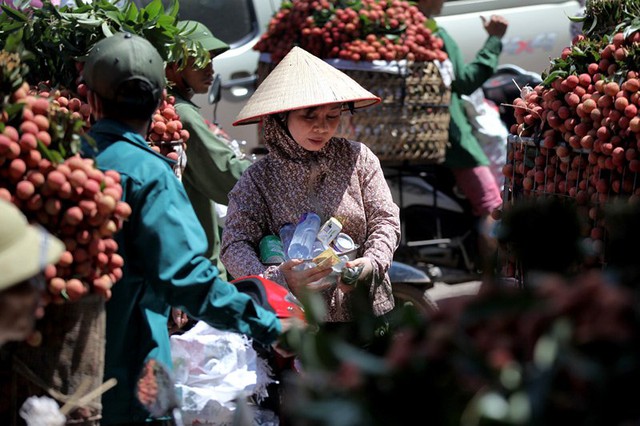 Một phụ nữ mang nước giải khát len lỏi trong dòng phương tiện ùn tắc bán cho những nông dân đang khát khô họng